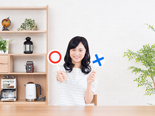 マルとバツの札を持つ女性