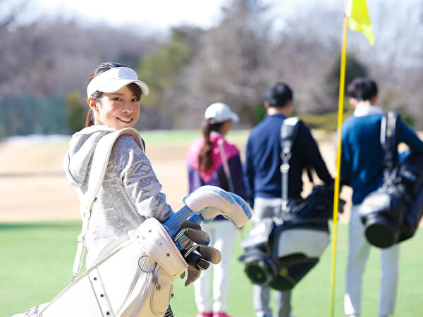 グリーンでキャディバッグを担ぐ女性