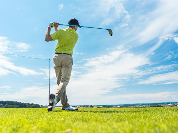 快晴のコースでスイングをする男性
