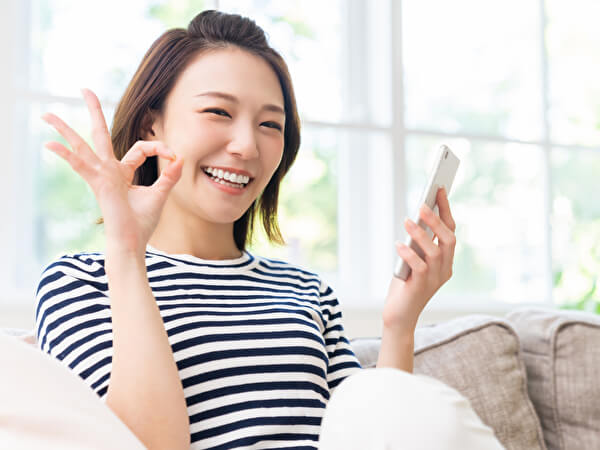 スマホを手に持ち笑う女性