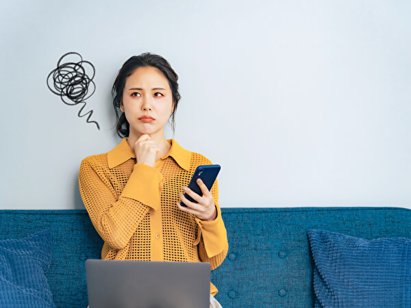 スマホを持って悩む女性